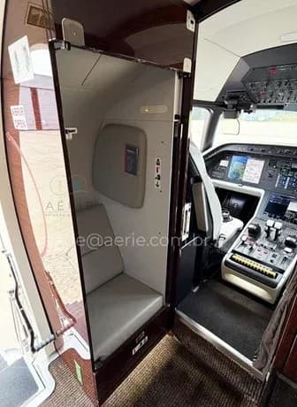 A view from the cabin looking into the modern glass cockpit of the Embraer Praetor 600, with a small seat to the left.