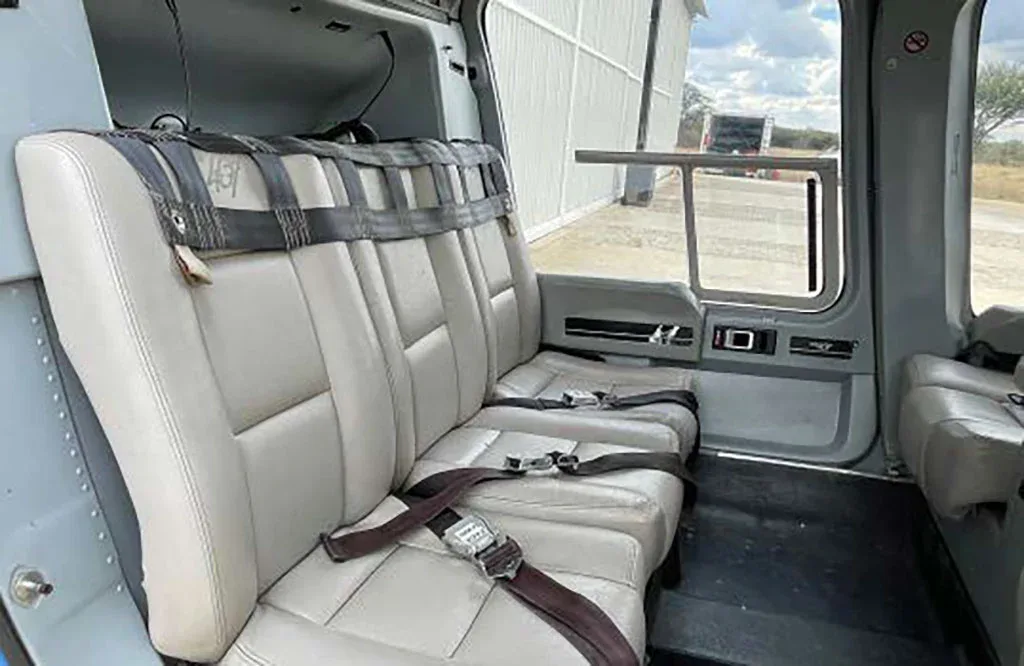 The rear bench seating of a helicopter cabin, with seatbelts visible.