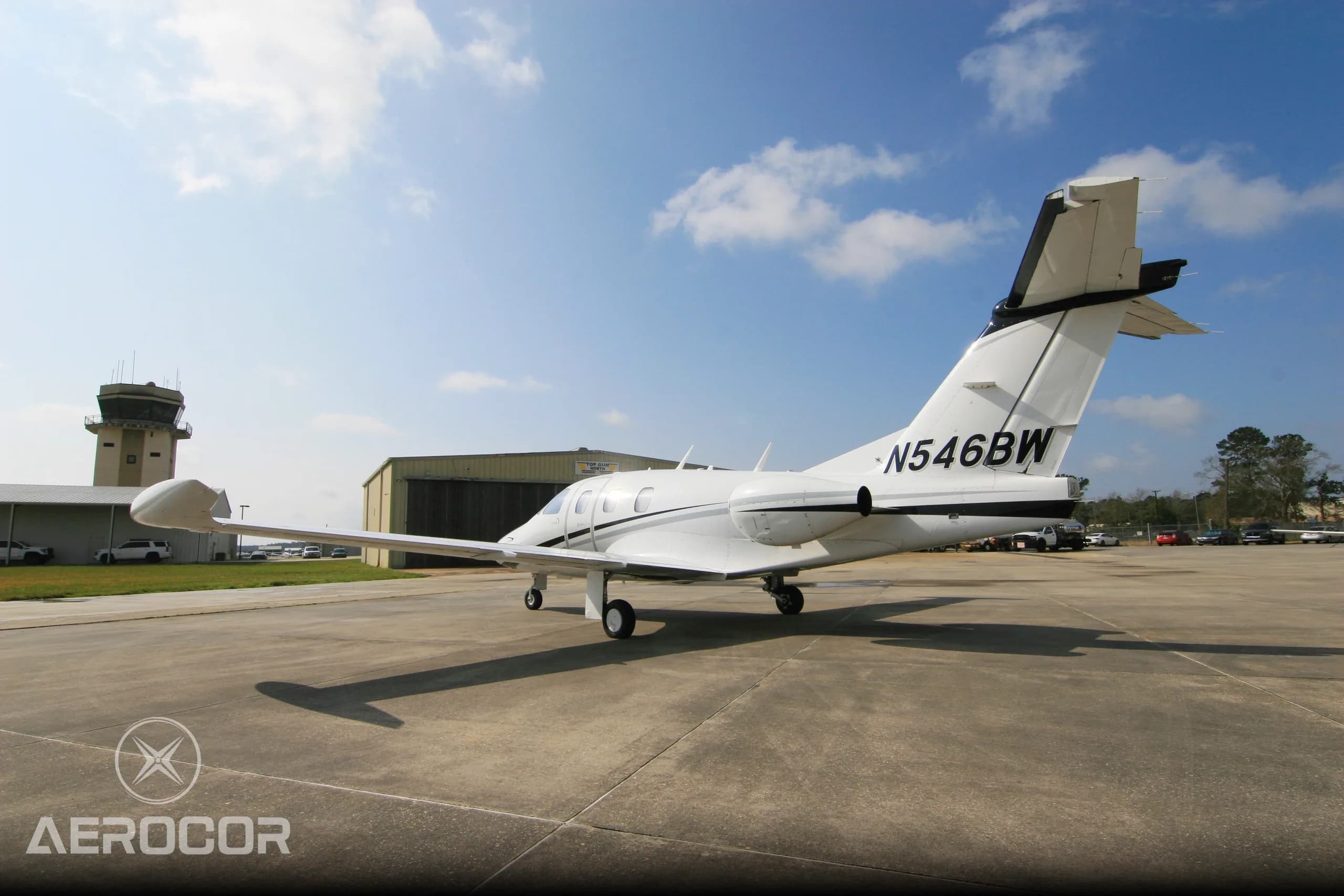 Rear-right view of a white Eclipse 500 jet with black and grey stripes parked on an airfield.