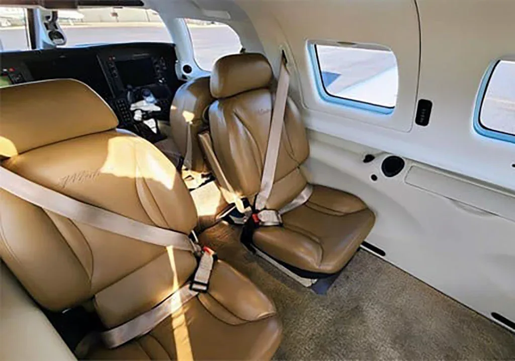 The tan leather interior cabin of the aircraft, showing two passenger seats and a view towards the cockpit.