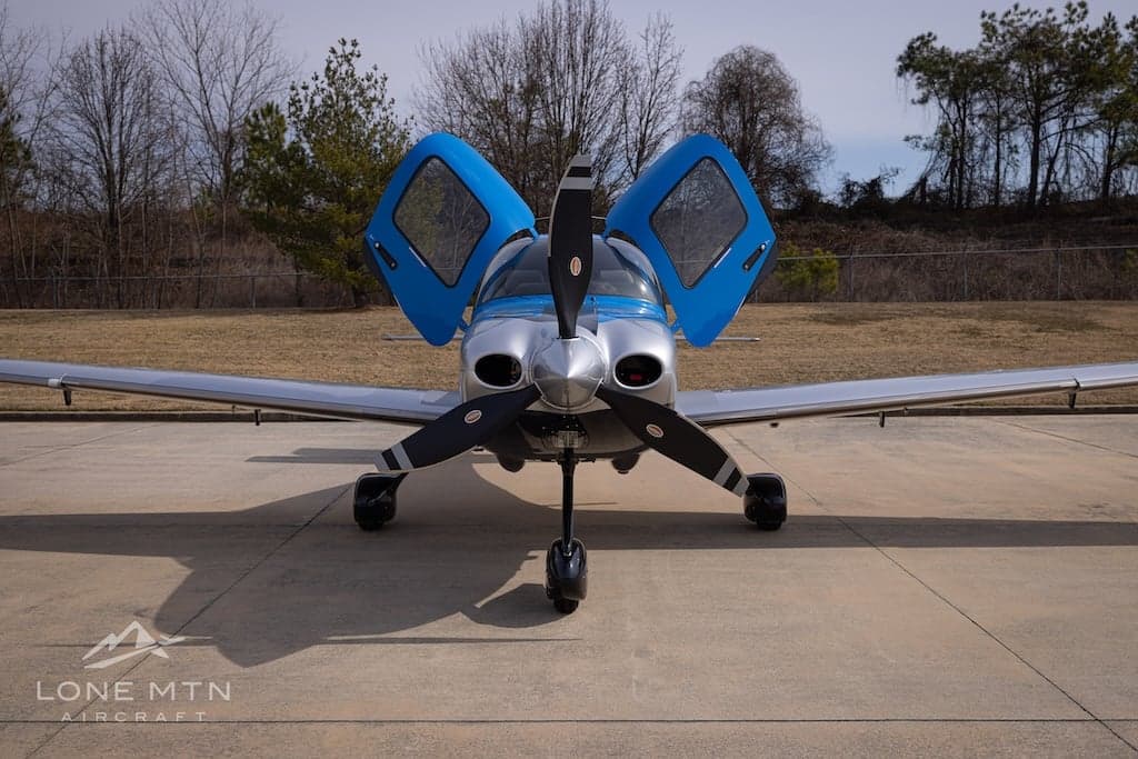 Front view of a Cirrus SR22T with blue and silver paint scheme on the ramp with doors open.