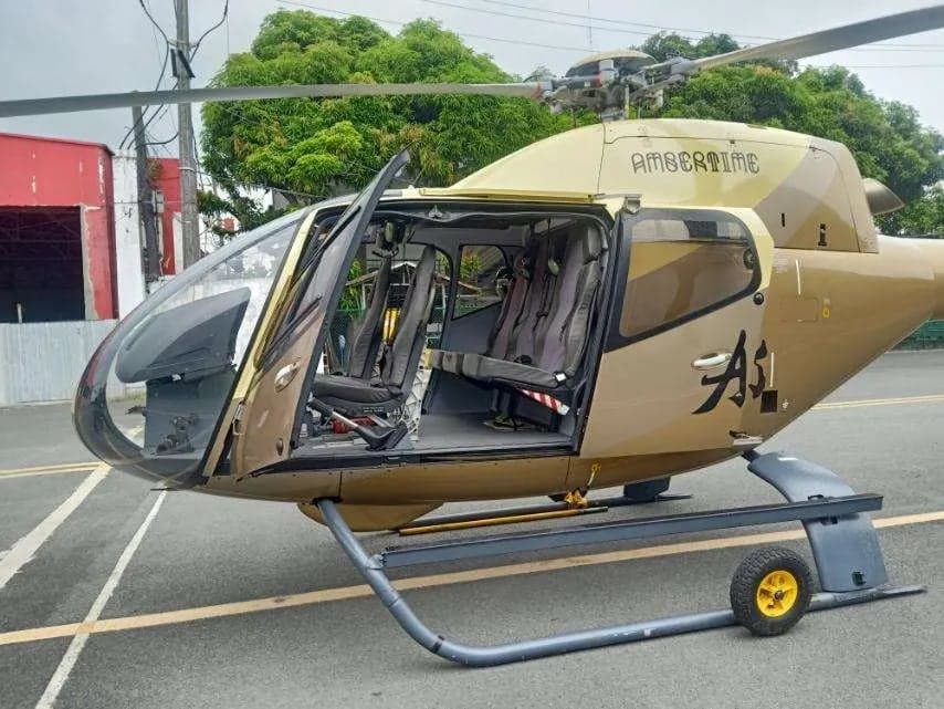 Front side view of a gold helicopter with the door open, showing the interior.