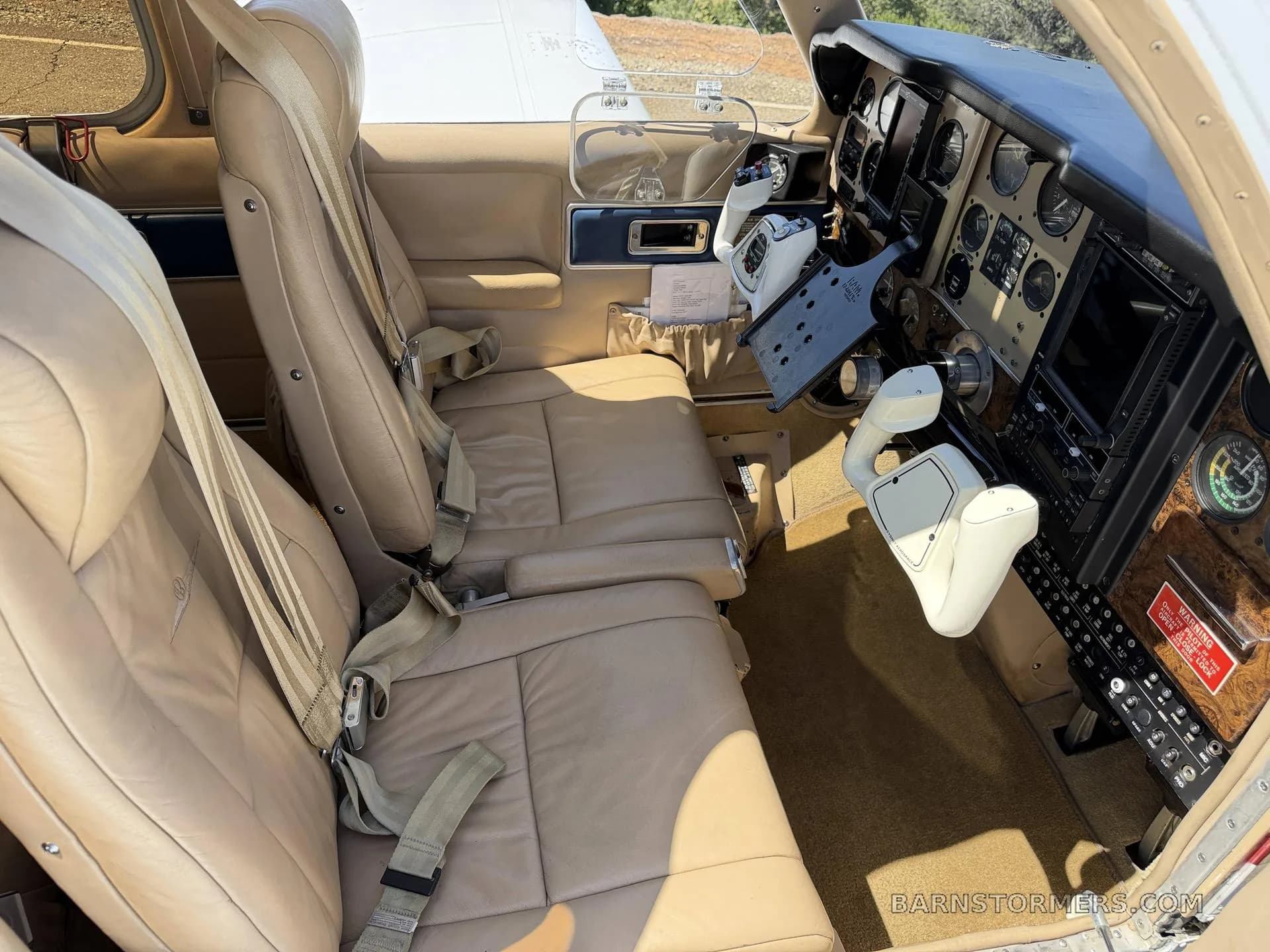The tan leather front seats and part of the cockpit of a small aircraft.