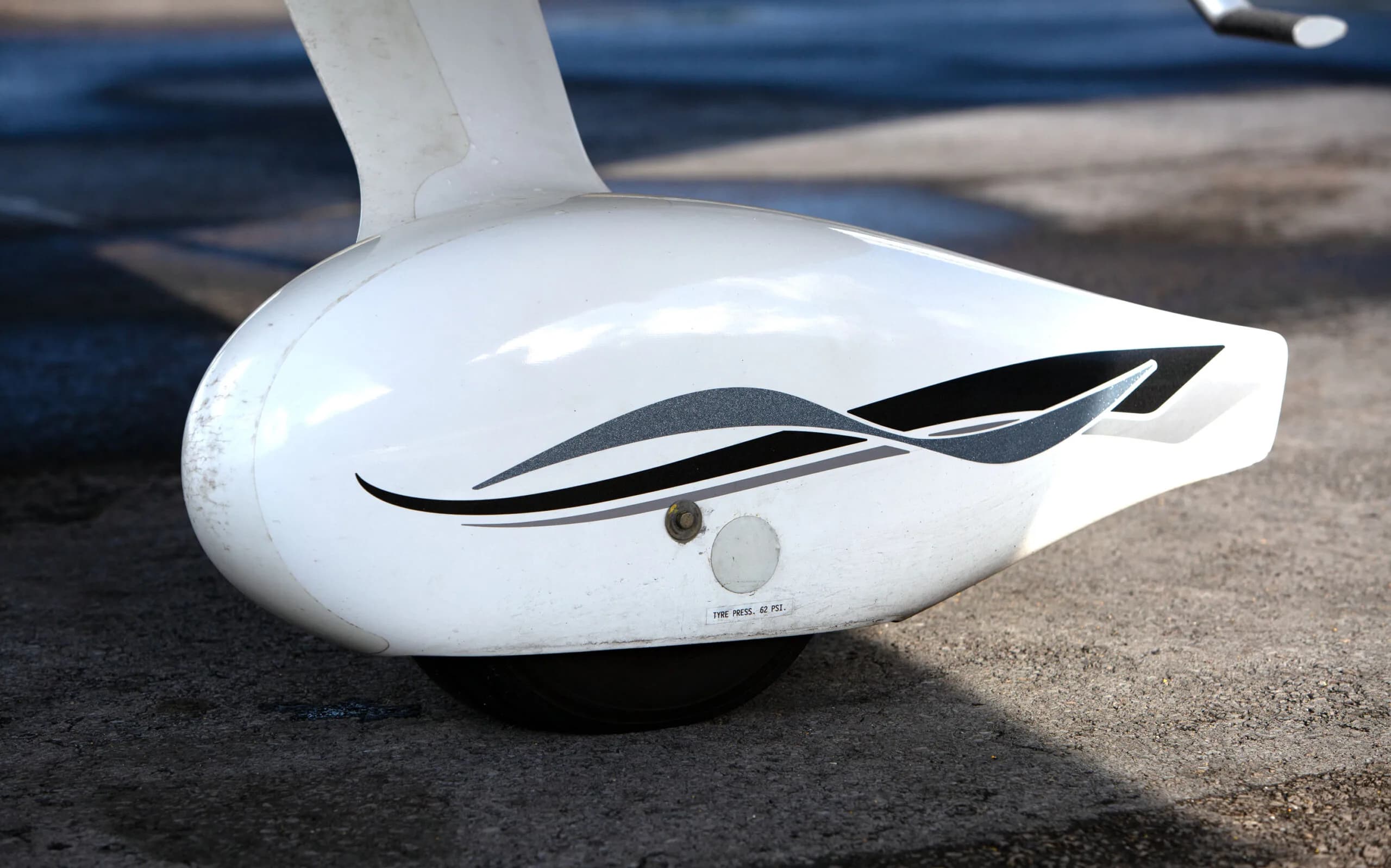 A close-up view of the white main landing gear fairing of a Cirrus SR22 G3 aircraft, showing black and grey stripe details and tire pressure markings.