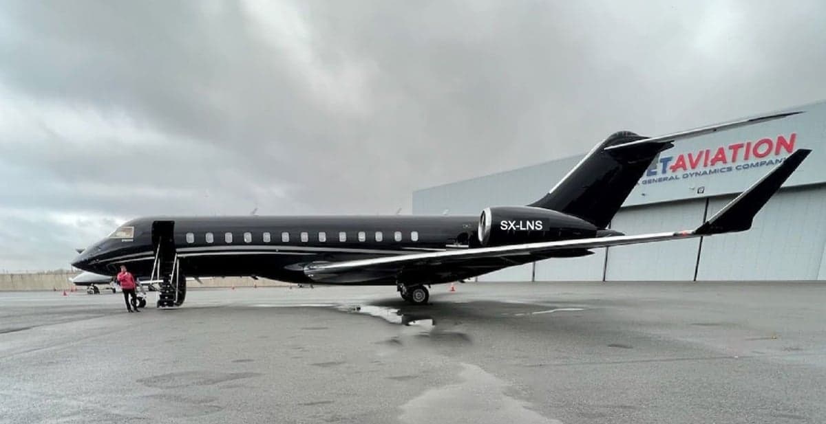 A black Bombardier Global Express XRS aircraft with the tail number SX-LNS parked on the tarmac.