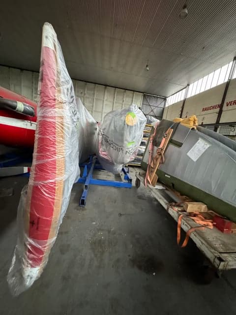 Aircraft parts wrapped in plastic in a hangar.
