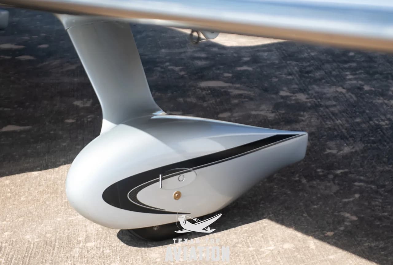A close-up view of the Cirrus SR22 aircraft's silver main landing gear fairing with a black stripe.