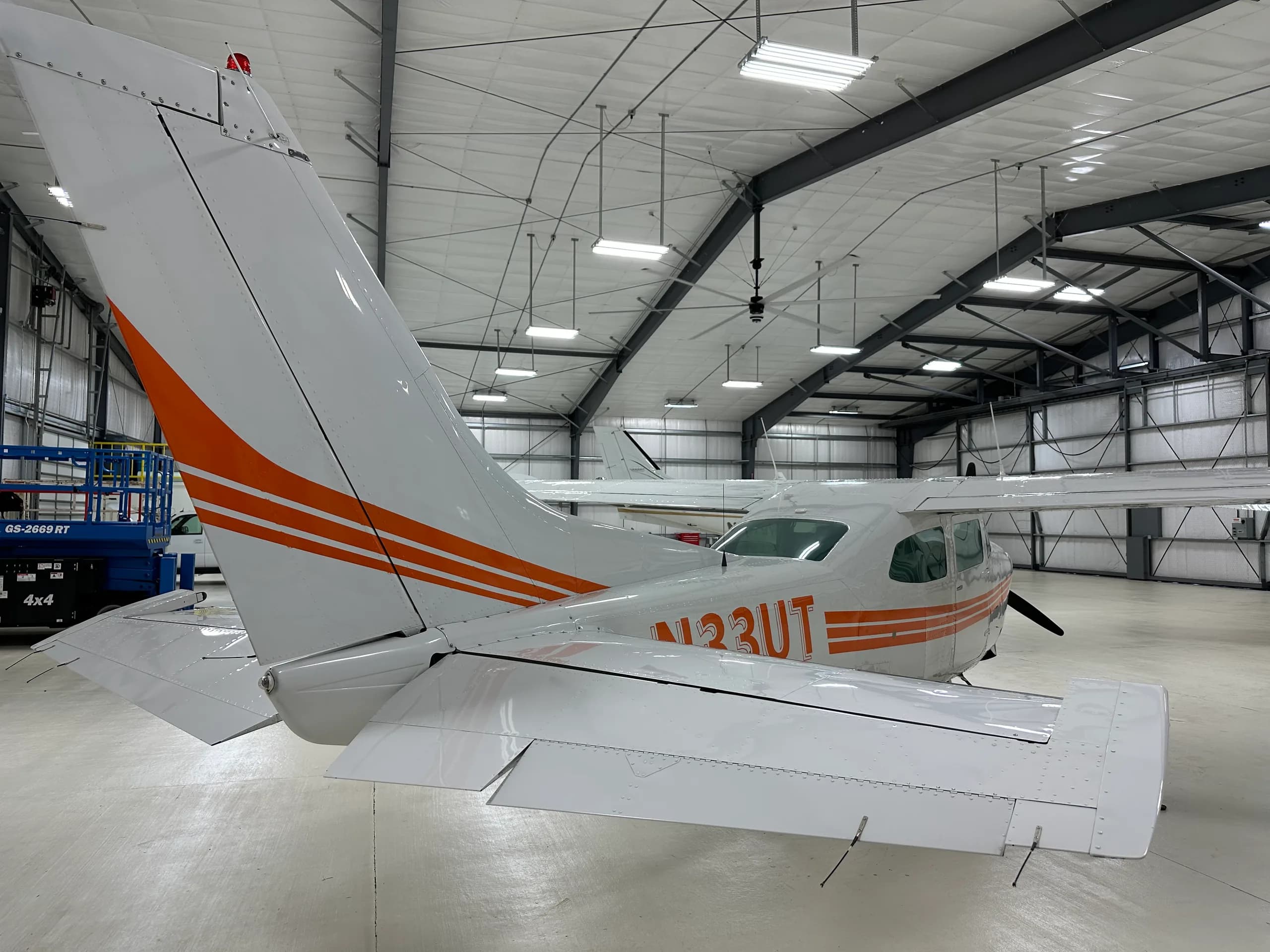 A Cessna 206 Stationair aircraft with orange stripes parked in a hangar.
