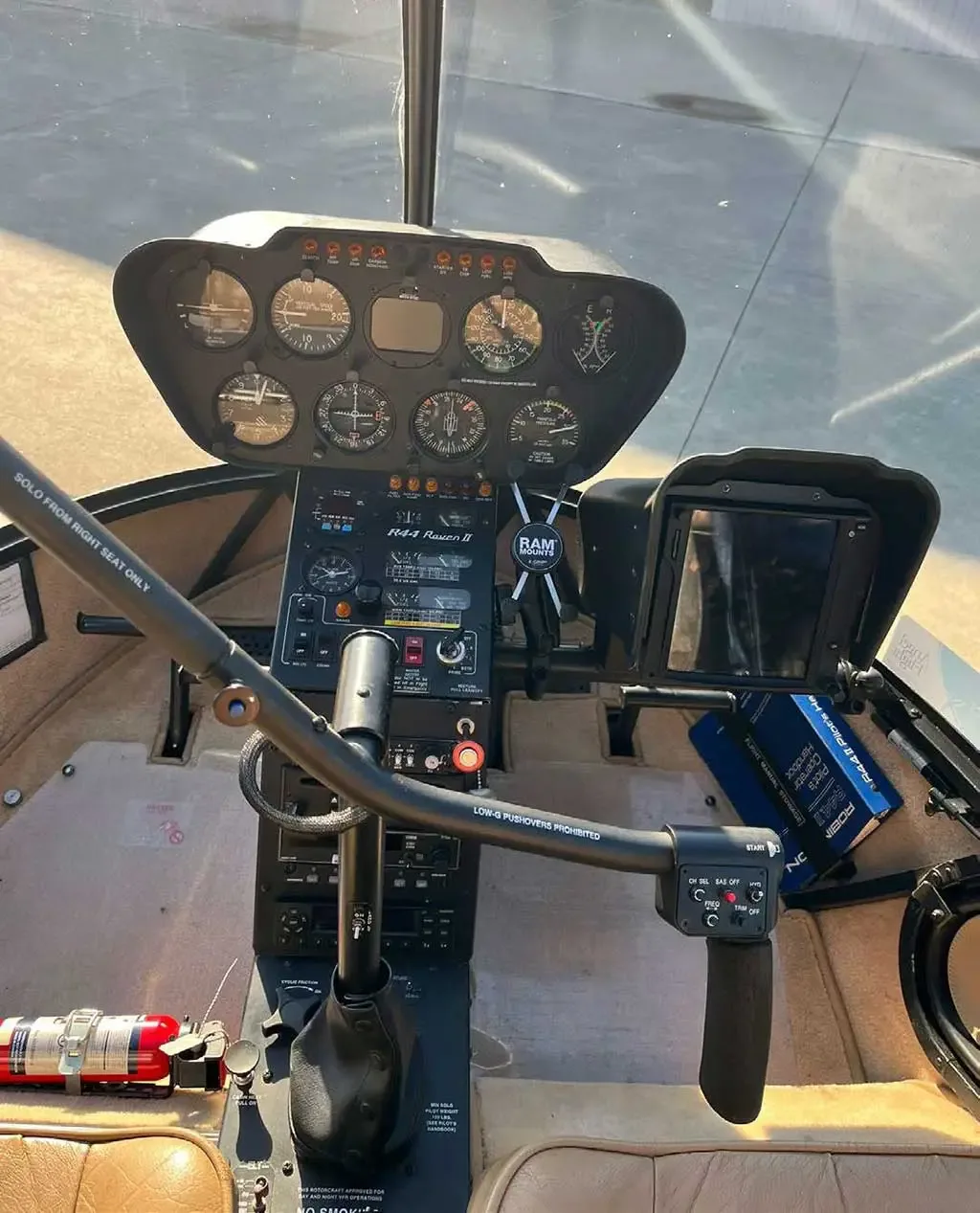A wider view of the Robinson R44 Raven II helicopter cockpit, showing the instrument panel and controls.