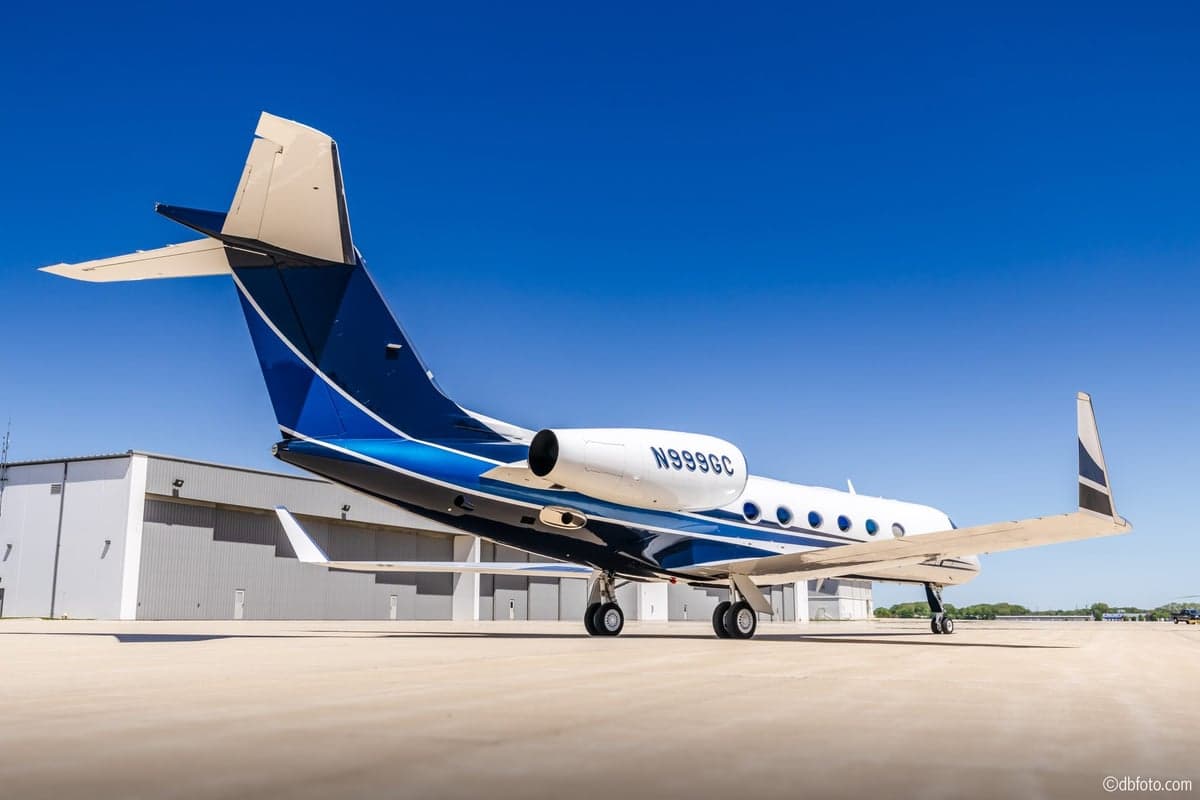 A rear view of the N999GC Gulfstream G550 business jet, highlighting its distinctive blue and black tail design.