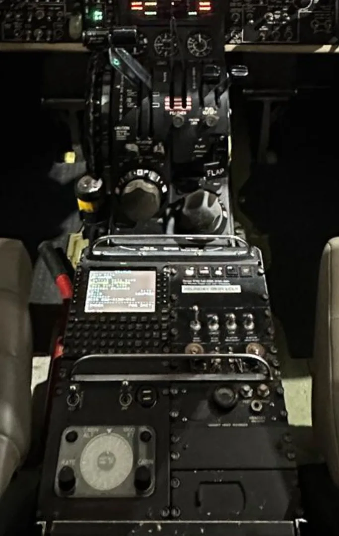 A close-up view of the center console and lower instrument panel in an aircraft cockpit, showing various controls and a display.