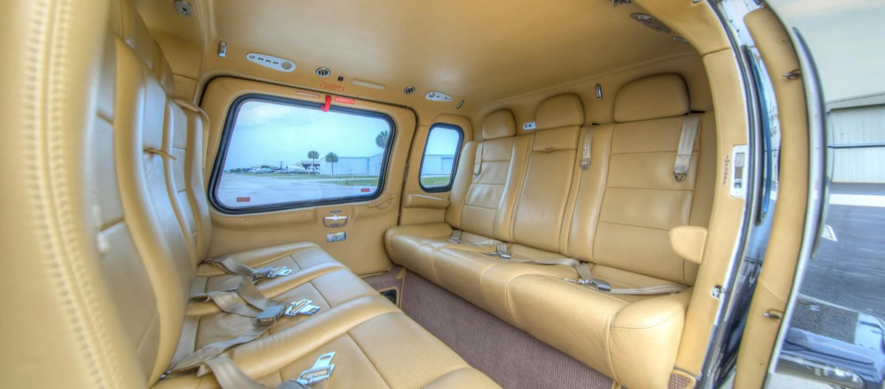 View of the helicopter cabin with tan leather seats and windows.