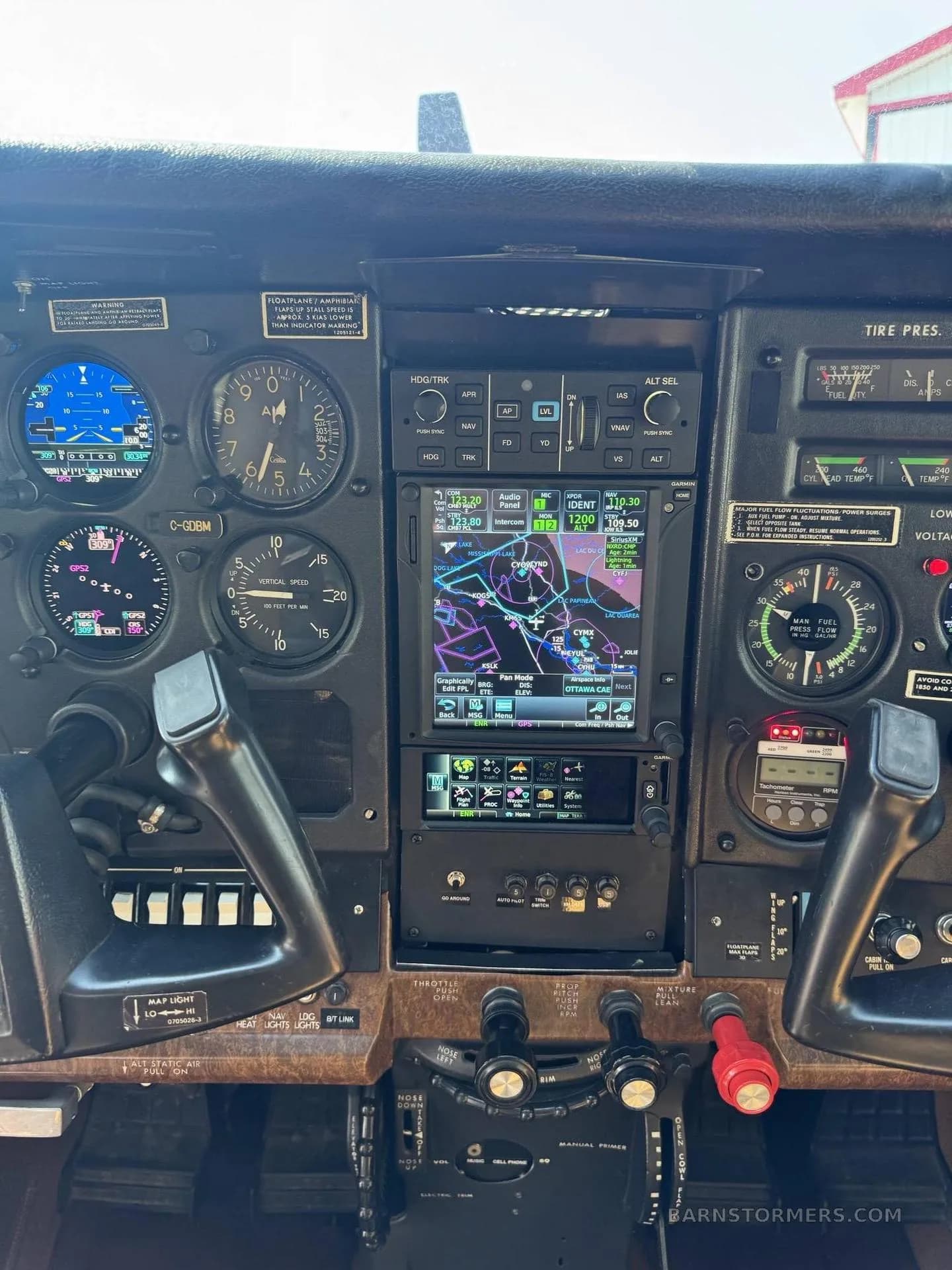 A detailed view of the center avionics stack in the Cessna Stationair 6 cockpit, featuring a large GPS display.