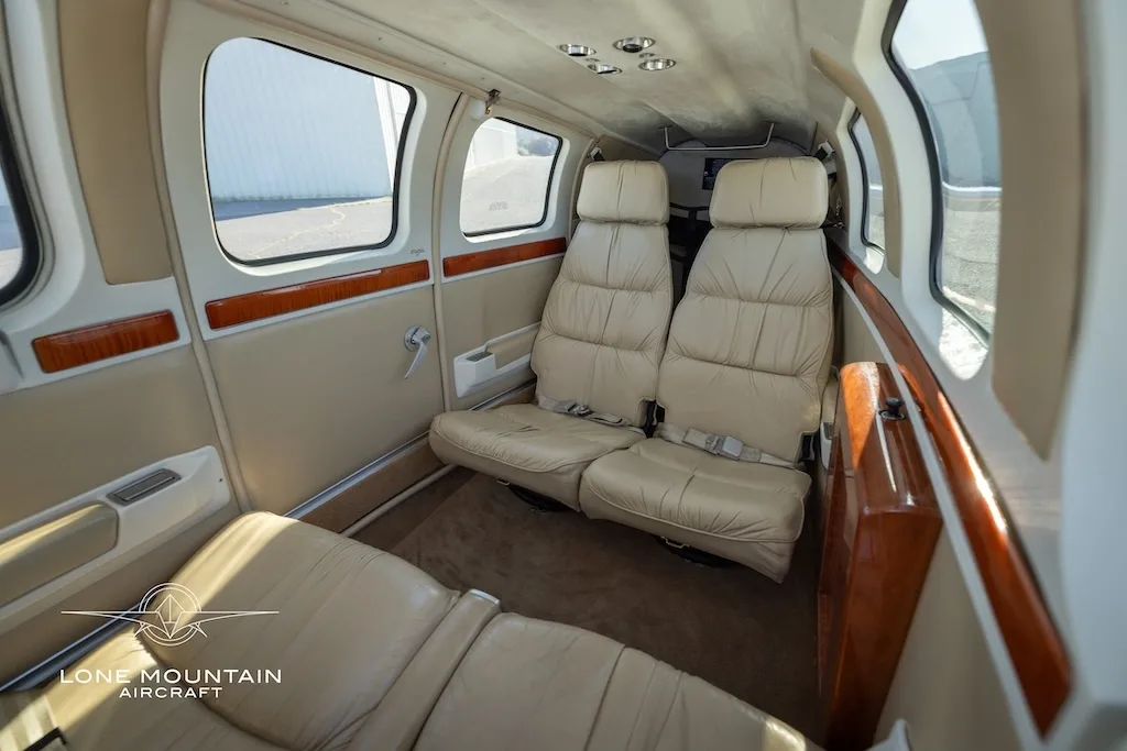 The beige leather interior cabin of the aircraft, showing two rear seats and a side table from a different angle.