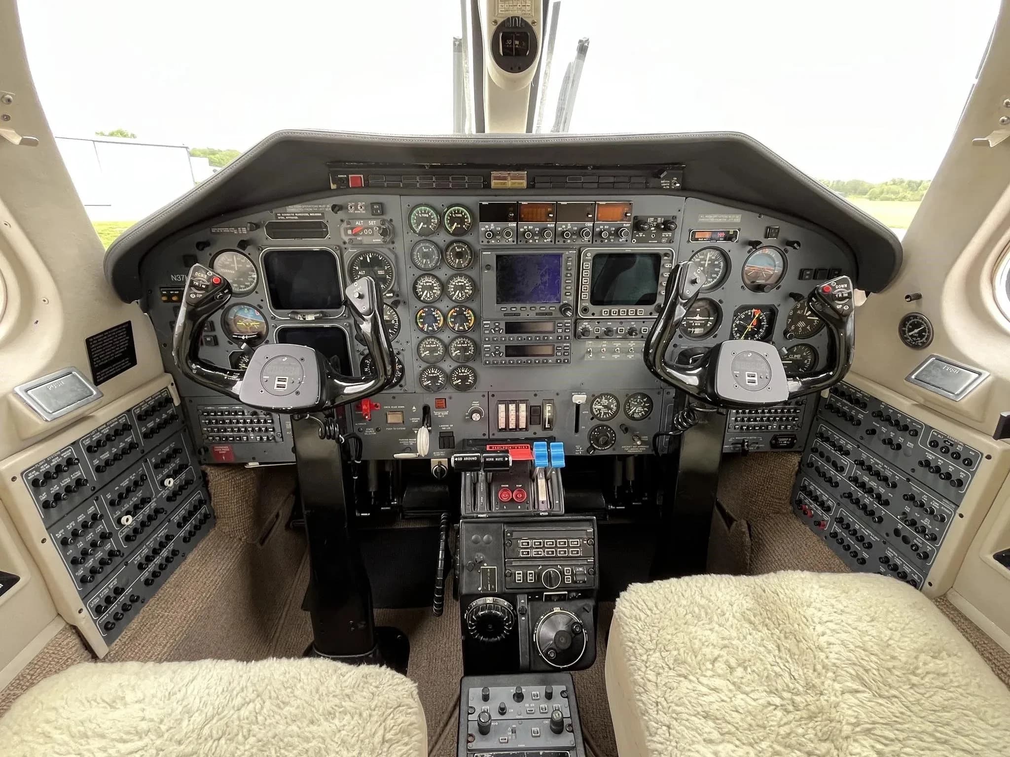 View of the cockpit of a twin-engine turboprop aircraft, showing the instrument panel with multiple gauges and two control yokes.
