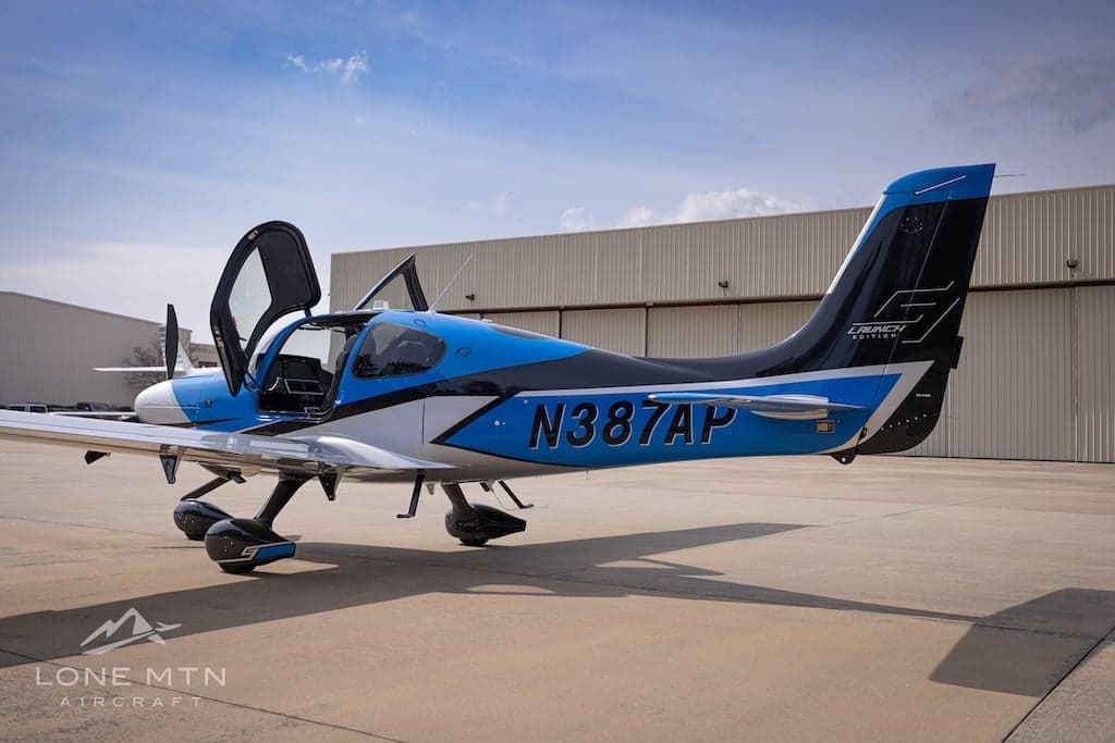 Cirrus SR22T with blue and silver paint scheme on the ramp with doors open.
