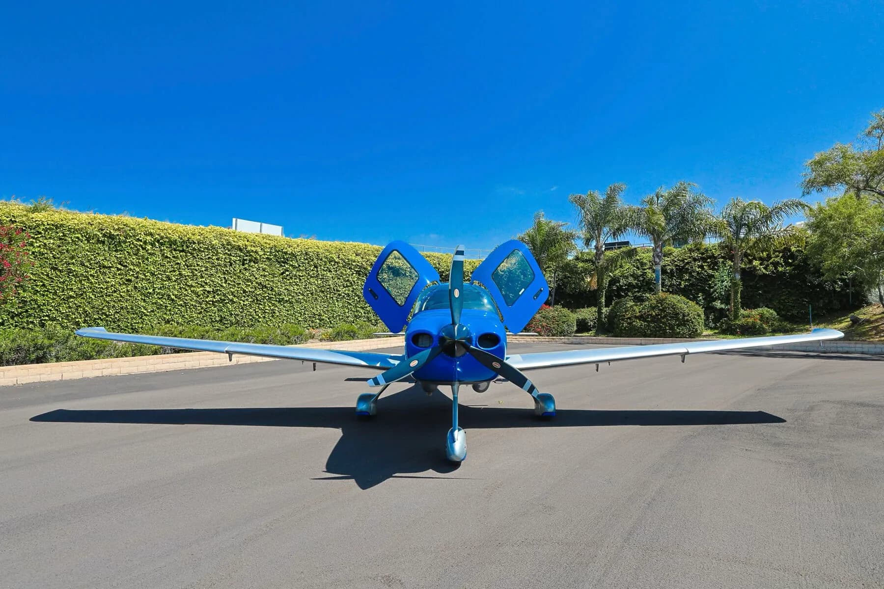 A head-on view of the blue and silver Cirrus SR20 aircraft N333YY with its gull-wing doors open, parked on an asphalt ramp.