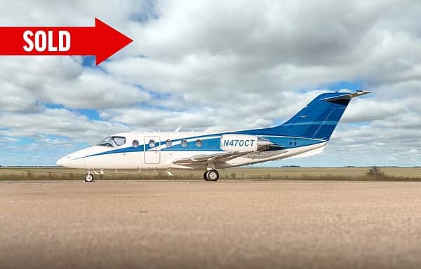 Side view of a white and blue Eclipse 500 jet on the tarmac with a SOLD banner.