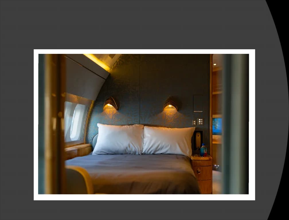 A private jet bedroom with a large bed, two pillows, and wall-mounted lamps.
