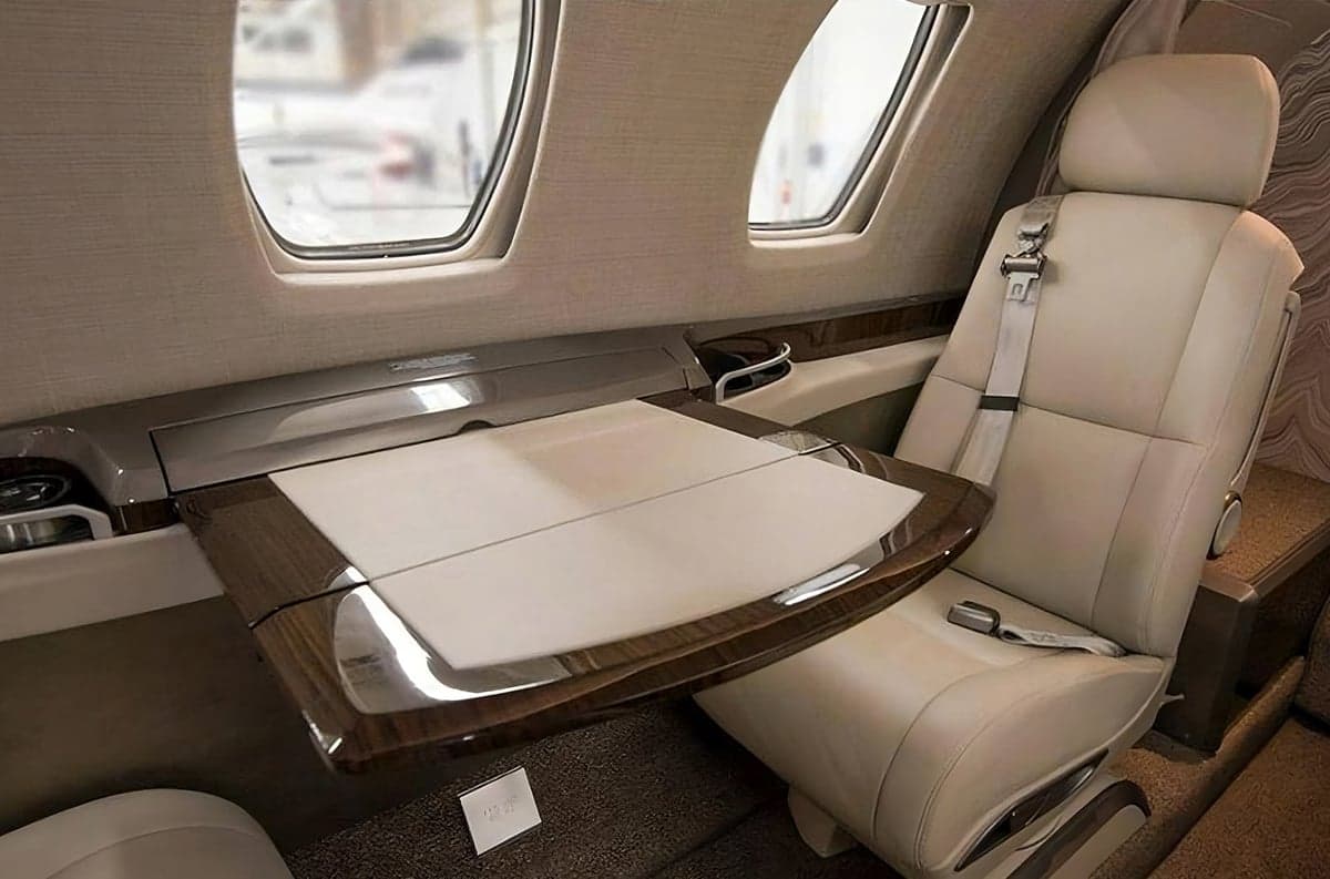 A single seat and table in the cabin of a jet.