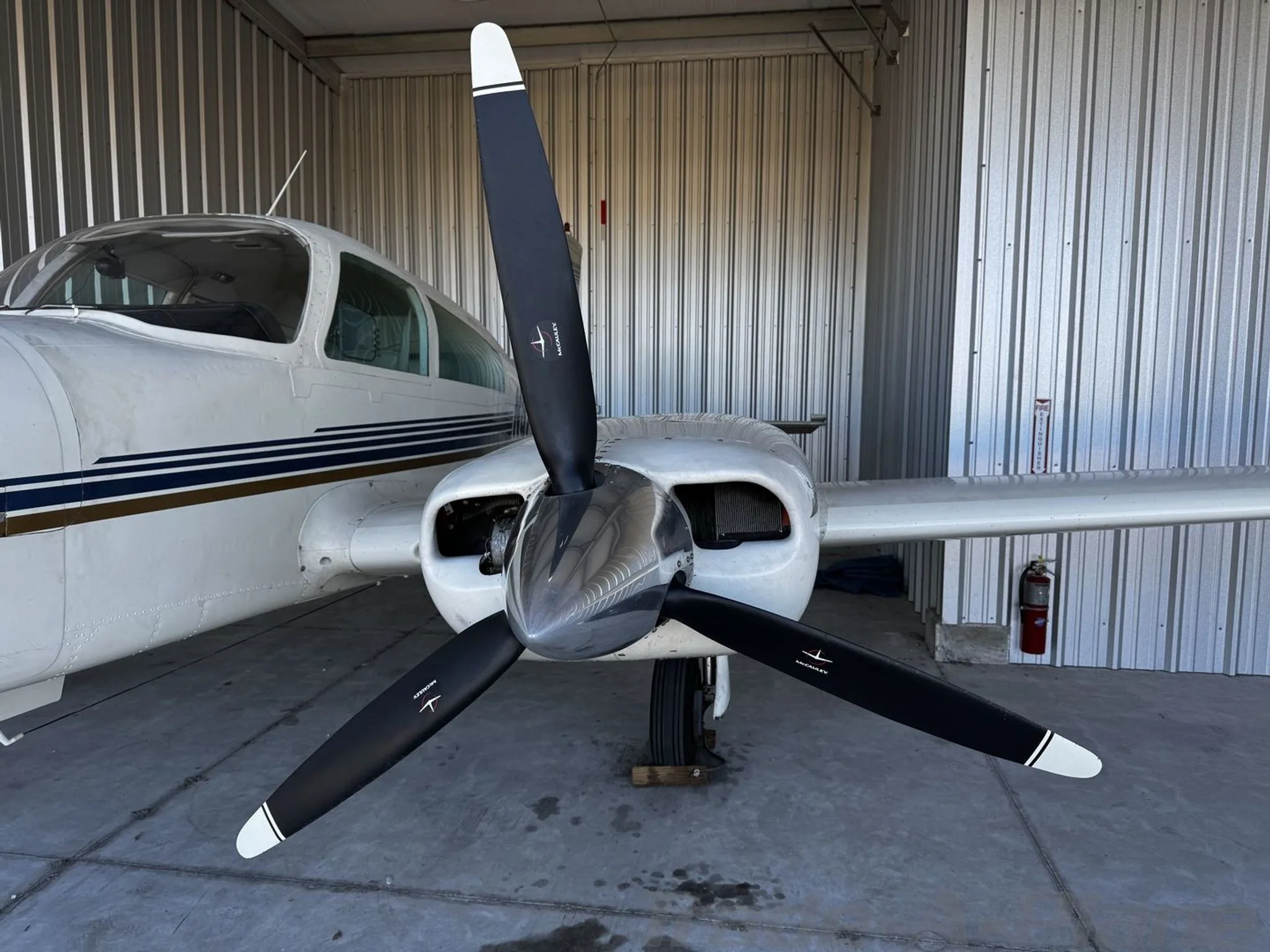 A close-up view of the aircraft's right engine and three-bladed propeller inside a hangar.