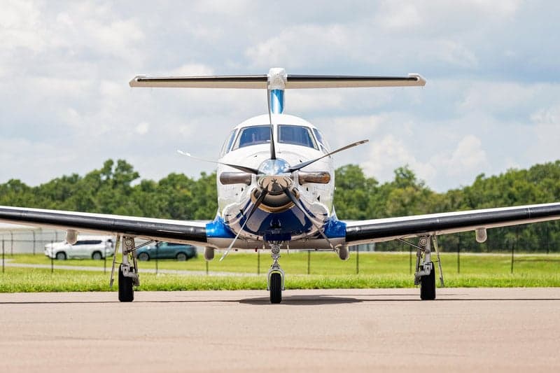 Front view of a Pilatus PC-12 aircraft with a blue and white paint scheme parked on the tarmac.