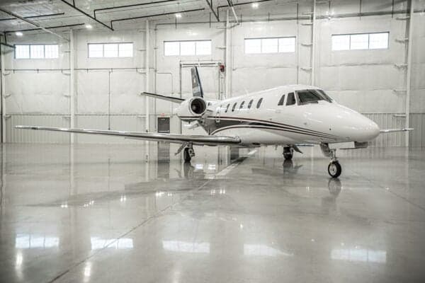 A Citation jet, N338HR, is parked in a hangar.