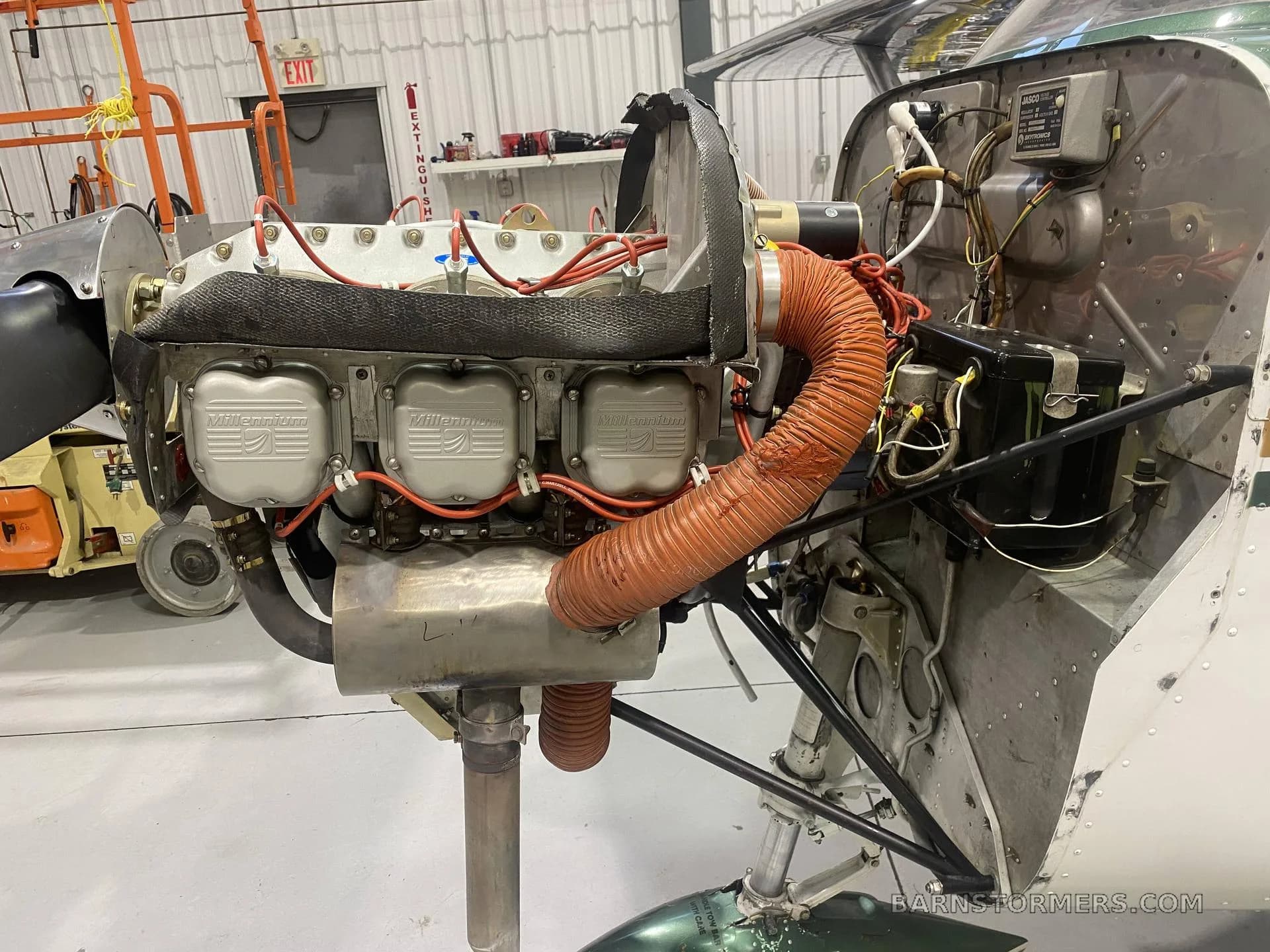 A close-up view of the exposed aircraft engine, showing the Millennium cylinders and orange air ducts.
