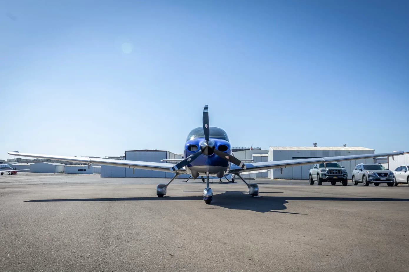 A front view of the blue and silver Cirrus SR22 aircraft, N275MG, parked on an airport tarmac.