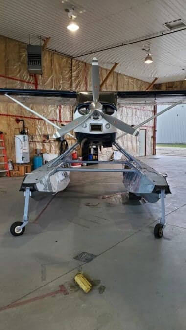 Front view of a Cessna on floats inside a hangar.
