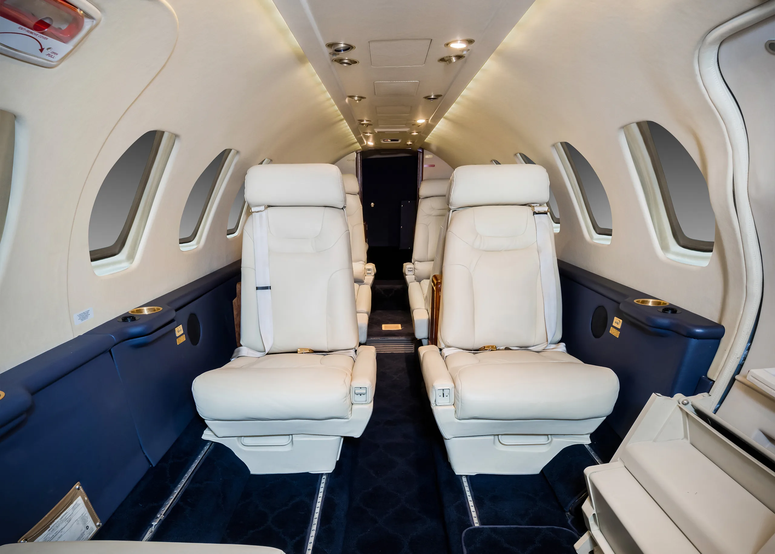 Interior view of the aircraft cabin with white leather seats and blue accents.