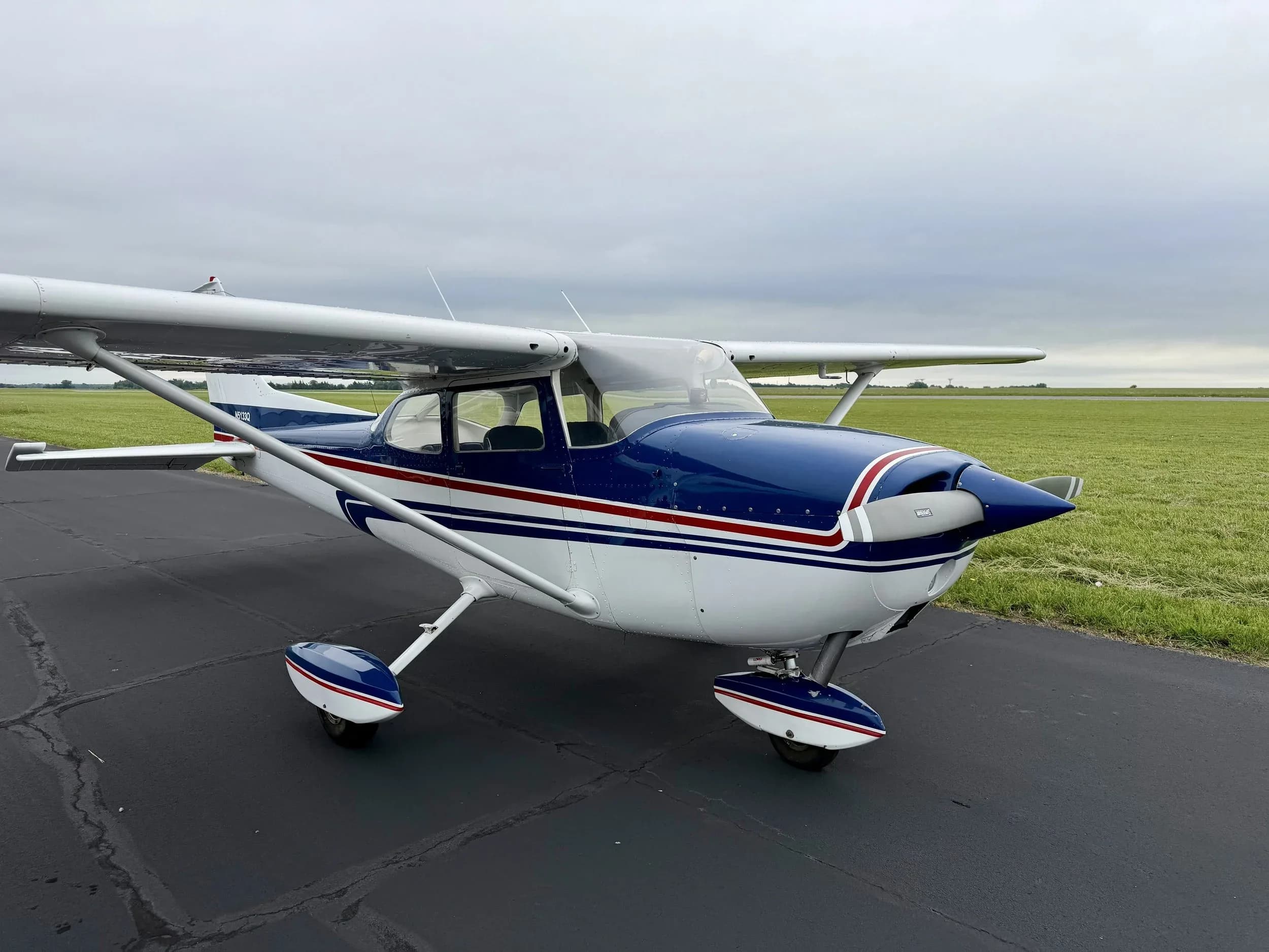 A front-quarter view of the blue and white Cessna 172 aircraft N5133Q on the tarmac.