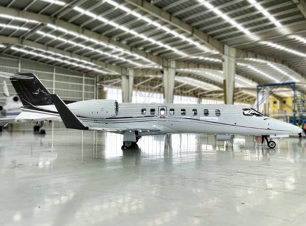 Side view of a light gray jet aircraft parked inside a hangar.