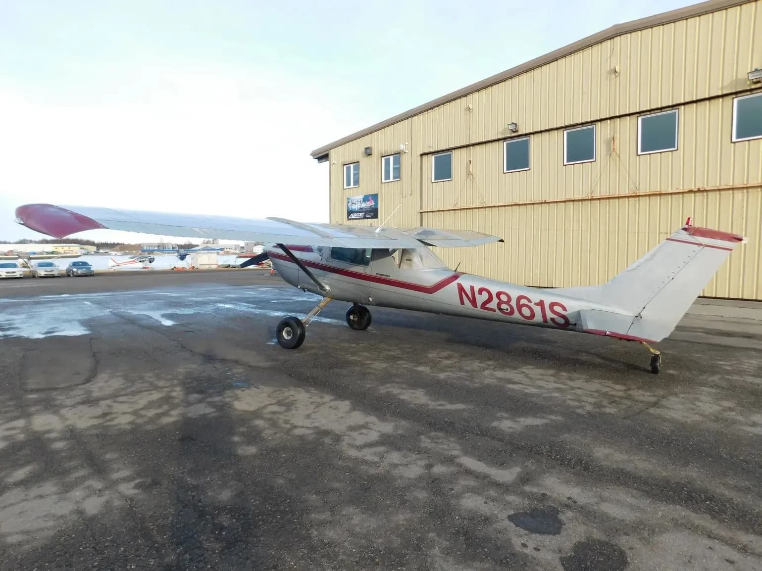A silver and red single-engine propeller aircraft (N2861S) parked on a tarmac, viewed from the rear-left.