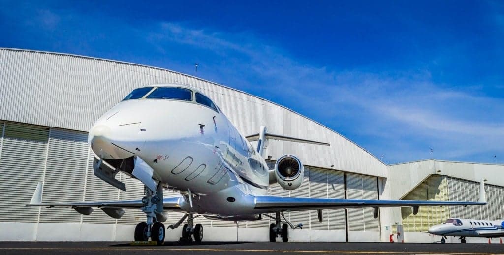 A Bombardier Challenger 300 parked on the tarmac in front of a hangar.