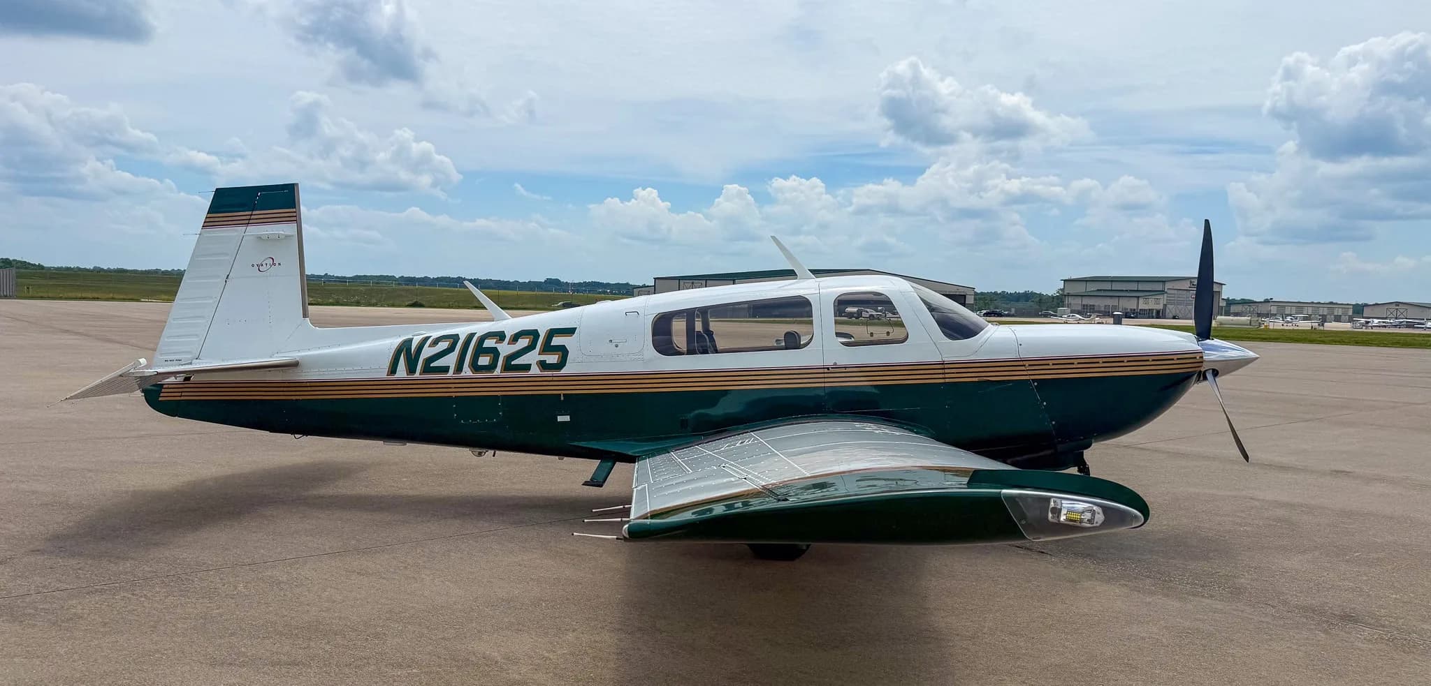 A front-side view of the white and green Mooney M20 aircraft with registration N21625 on an airfield.