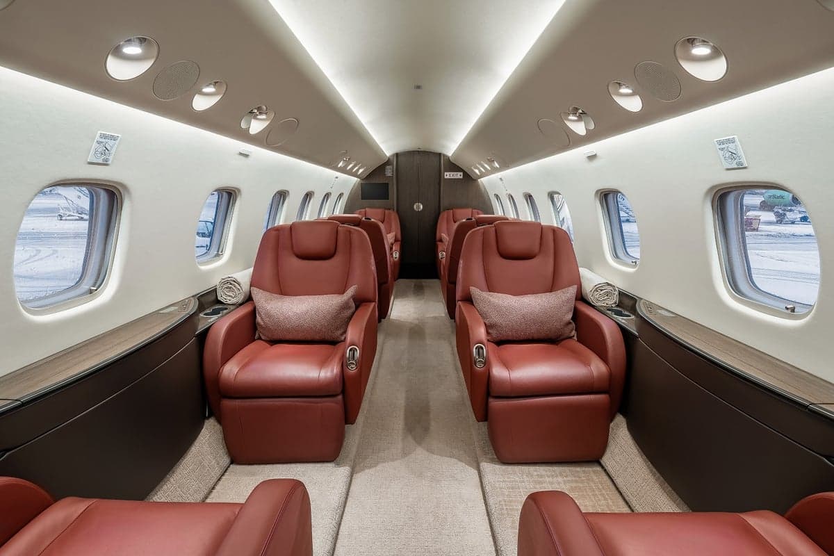 View of the aircraft interior with red leather seats and a neutral color scheme.
