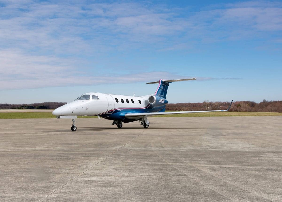 A white and blue jet, N82P, sits on the tarmac.