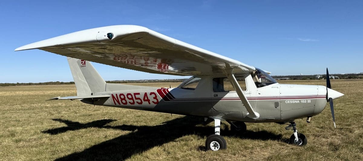 A Cessna 152 II aircraft with registration number N89543 parked on a grassy field.