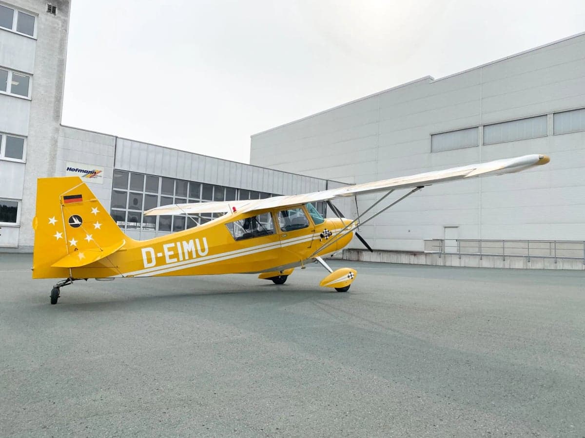 A yellow and white aircraft, D-EIMU, parked on the tarmac.