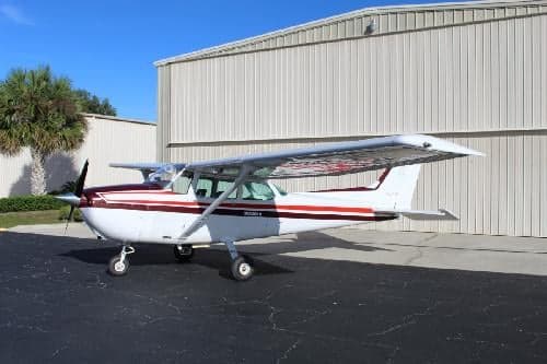 A Cessna 172 Skyhawk with a white and maroon paint scheme parked on the tarmac.