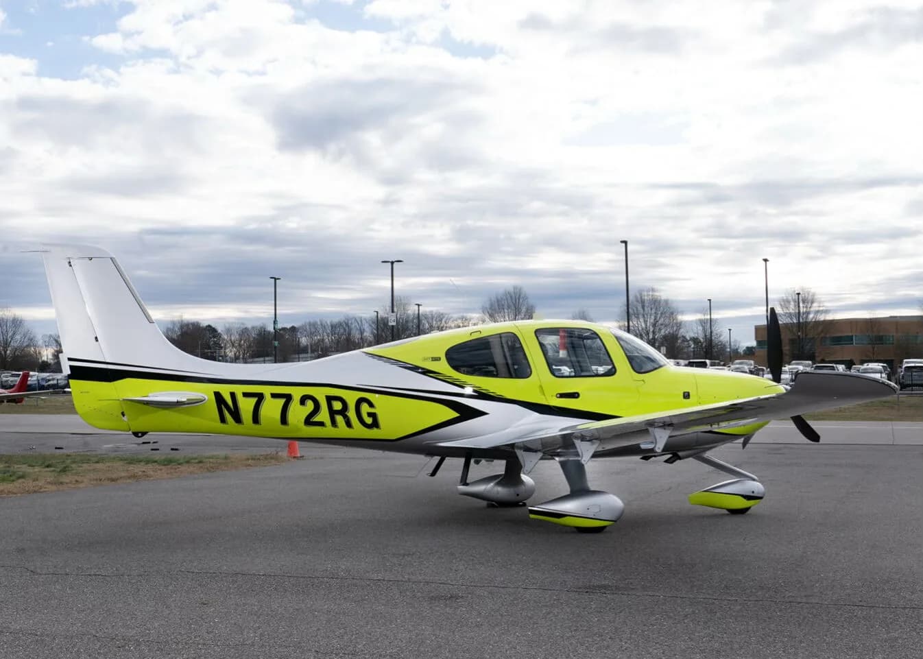 A Cirrus SR22 aircraft with a bright yellow and silver paint scheme, registration N772RG, parked on an airfield.