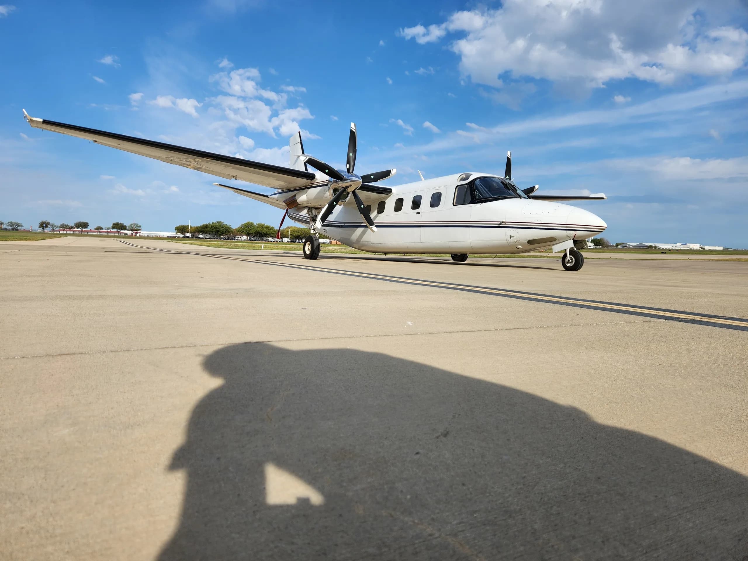 A white and black Commando aircraft is parked on the tarmac on a sunny day.