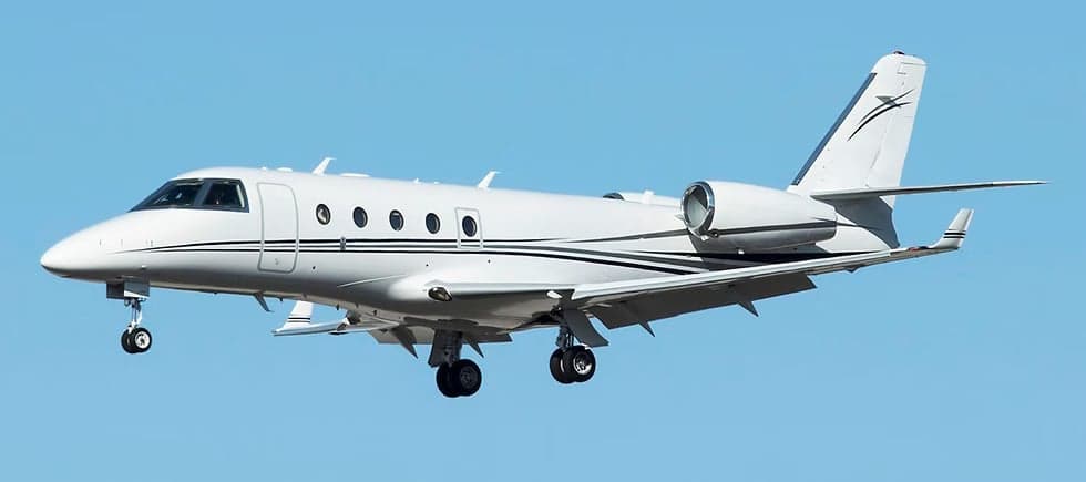 A white jet aircraft with black stripes is shown in flight against a clear blue sky.