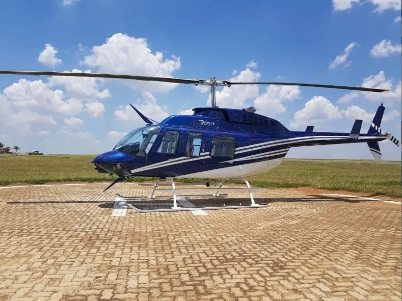 A blue and white Bell 206L-4 helicopter on a helipad.