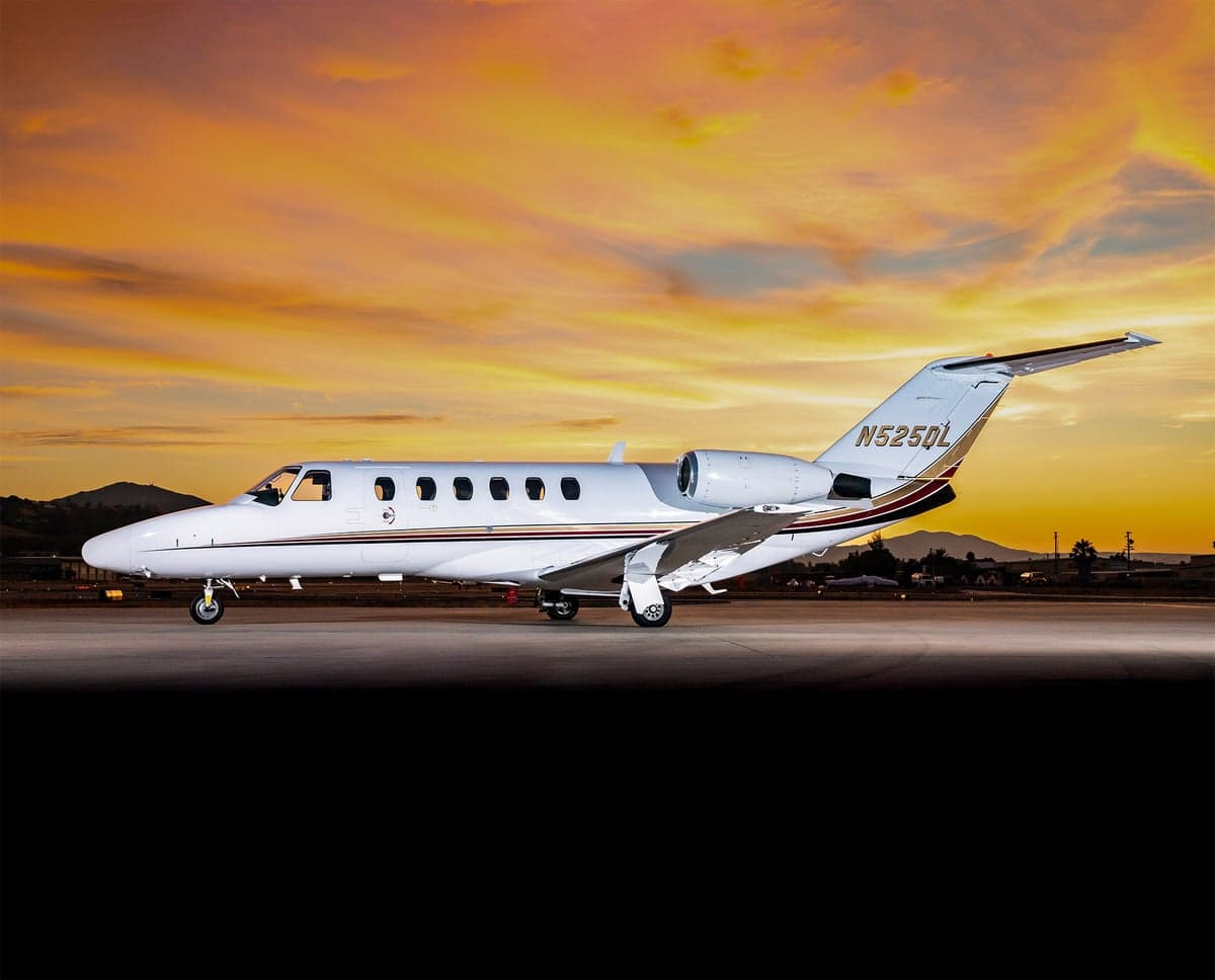A Cessna Citation CJ2 sits on the tarmac at sunset.