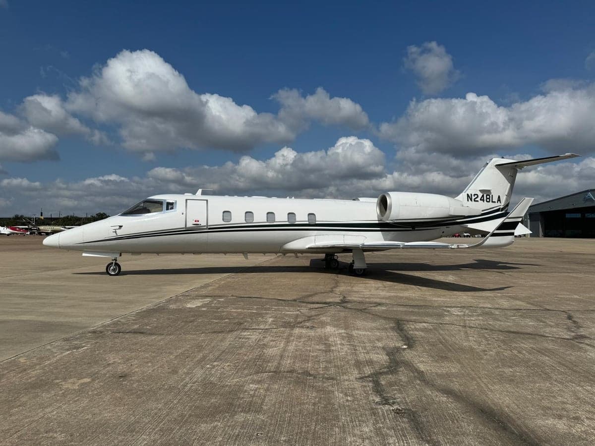 Side view of the Learjet 45XR, registration N248LA, on the tarmac under a partly cloudy sky.