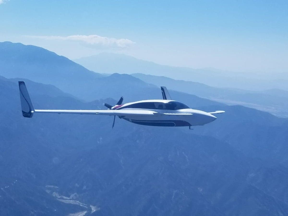 N7779X aircraft in flight over a mountainous landscape.