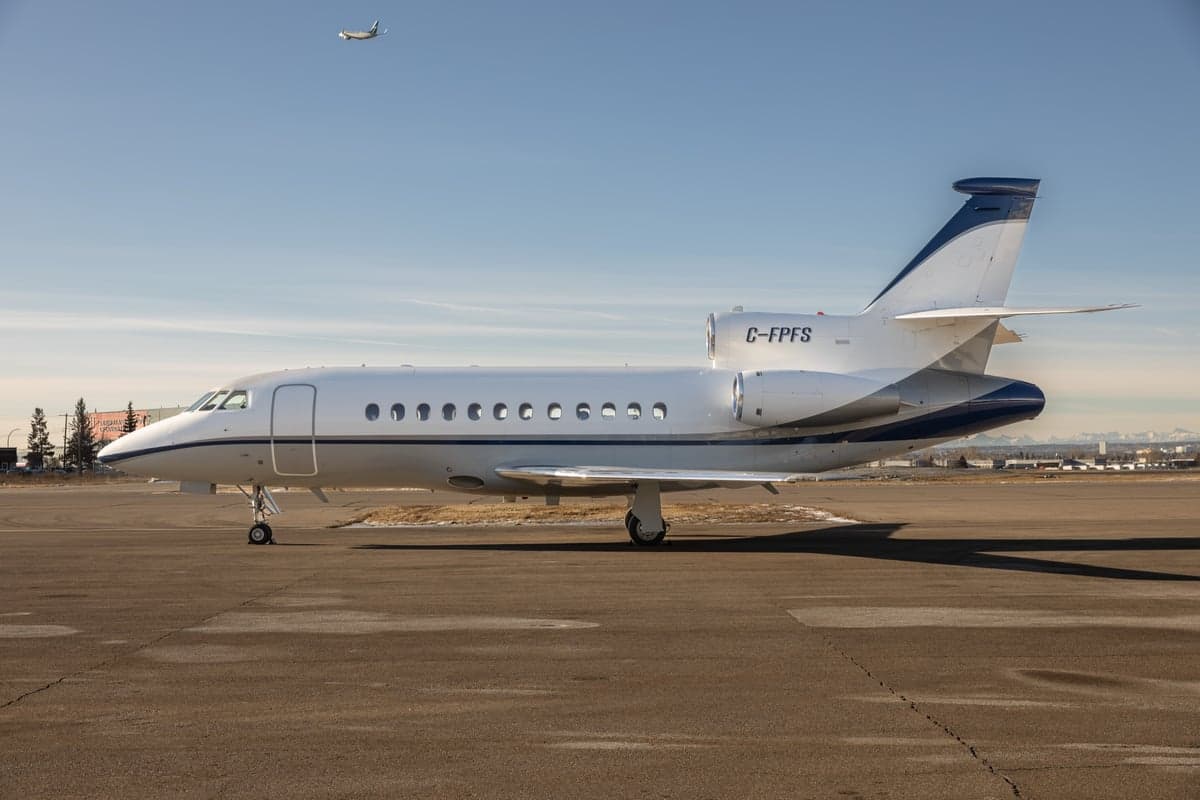 A Dassault Falcon aircraft with registration C-FPFS is parked on the tarmac.