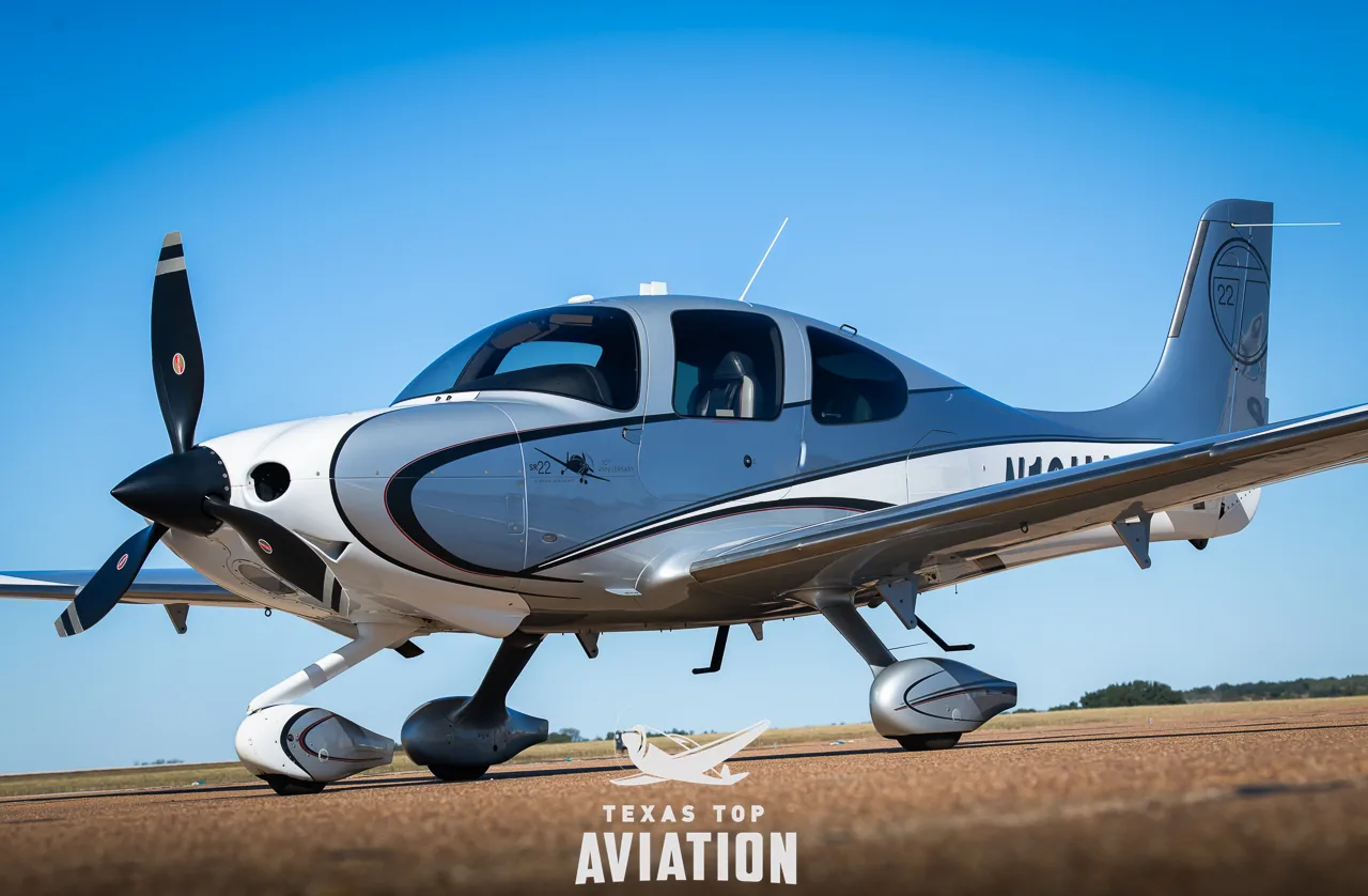 Front-left view of a silver and white Cirrus SR22 aircraft (N10UA) on an airfield.